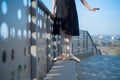 Ballerina in ballet legs in shoes and black tutu dancing by the fence. Beautiful young woman in black dress and pointe