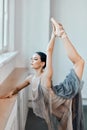 Ballerina bends back, standing on one leg doing stretching, lifting leg up high.