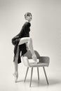 ballerina in a black dress stands showing a deflection and plasticity and putting her foot on a chair Royalty Free Stock Photo