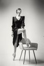 ballerina in a black dress stands showing a deflection and plasticity and putting her foot on a chair Royalty Free Stock Photo