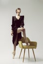 ballerina in a black dress stands showing a deflection and plasticity and putting her foot on a chair Royalty Free Stock Photo