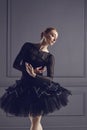 Ballerina in a black tutu posing on a black background.