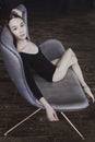 ballerina in a bodysuit and pointe shoes is sitting on a sofa in a loft with her hands behind her head