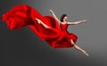 Ballerina Dance. Ballet Dancer in Red Dress jumping Split. Woman in Ballerina Shoes dancing in Silk Gown flying on Wind over Gray Royalty Free Stock Photo