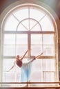 Ballerina is dancing in front of a large window