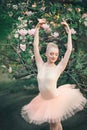 Ballerina dancing outdoors classic ballet poses in flowers lands