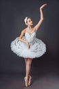 Ballerina dancing in white dress. Color photo. Graceful ballet dancer or classic ballerina dancing on grey studio