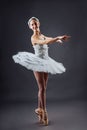 Ballerina dancing in white dress. Color photo. Graceful ballet dancer or classic ballerina dancing on grey studio