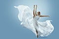 Ballerina doing Split in White flying Dress. Ballet Dancer jumping over Blue background. Freedom and Inspiration Concept. Carefree Royalty Free Stock Photo