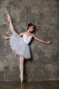 Ballerina doing the splits near gray wall