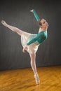 Ballerina in green leotard and skirt, dancing in the studio