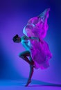 Ballerina jumping in Silk waving Dress. Ballet Dancer in Fantasy Neon Color Gown flowing in Air. Beautiful Girl dance with flying