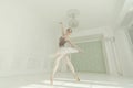 ballerina in a light bodysuit and tutu stands against the wall showing elements of ballet