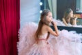 Girl wear pink dress sitting on a chair in the dressing room and make yourself a makeover. She holding brush Royalty Free Stock Photo