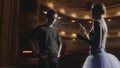 Ballerina with partner stands on theater stage