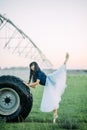 Ballerina performs swallow pose on farm near the wheel of agricultural sprayer Royalty Free Stock Photo