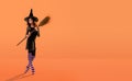 A ballerina on pointe shoes in a black witch costume in a hat and with a broom dances on an orange background