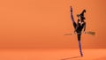 A ballerina on pointe shoes in a black witch costume in a hat and with a broom dances on an orange background