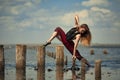 Ballerina in red dress is dancing in water on sea background.