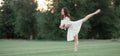 Ballerina stands in pose of swallow on lawn. Royalty Free Stock Photo