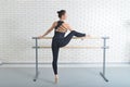 Ballerina stretches herself near barre at ballet studio, full length portrait. Royalty Free Stock Photo