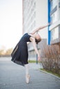 Ballerina in a tutu posing in front of a multi-storey residential building. Beautiful young woman in black dress and Royalty Free Stock Photo