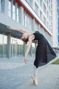 Ballerina in a tutu posing in front of a multi-storey residential building. Beautiful young woman in black dress and Royalty Free Stock Photo