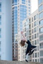 Ballerina in a tutu posing at a multi-storey residential building. Beautiful young woman in black dress and pointe shoes with