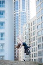 Ballerina in a tutu posing at a multi-storey residential building. Beautiful young woman in black dress and pointe shoes