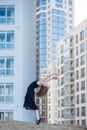 Ballerina in a tutu posing at a multi-storey residential building. Beautiful young woman in black dress and pointe shoes