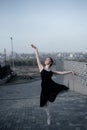 Ballerina in a tutu posing next to the fence. Beautiful young woman in black dress and pointe dancing over city Royalty Free Stock Photo