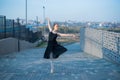 Ballerina in a tutu posing next to the fence. Beautiful young woman in black dress and pointe dancing over city Royalty Free Stock Photo