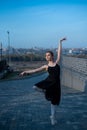 Ballerina in a tutu posing next to the fence. Beautiful young woman in black dress and pointe dancing over city Royalty Free Stock Photo