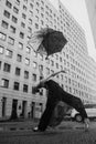 Ballerina with umbrella on city street under water drops
