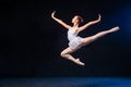 Ballerina in a white dress flying in a jump on black background Royalty Free Stock Photo