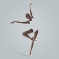 Ballerina. Young graceful female ballet dancer dancing over grey studio. Beauty of classic ballet. Royalty Free Stock Photo