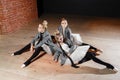 The ballet concept. Young ballerina girls relax sitting on the floor. Women at the rehearsal in a white tutu and a grey