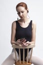 Ballet Concepts. Caucasian Female Ballet Dancer in Body Suit Sitting On Chair and Listening Music on Headphones. Against White