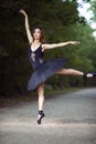 Ballet Concepts. Professional Japanese Female Ballet Dancer Posing in Black Tutu Against Forest Background And Beautifully Lifted