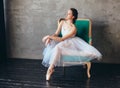 Ballet dancer ballerina in beautiful light blue dress tutu skirt posing sitting on vinage chair in loft studio Royalty Free Stock Photo