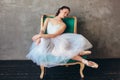 Ballet dancer ballerina in beautiful light blue dress tutu skirt posing sitting on vinage chair in loft studio Royalty Free Stock Photo