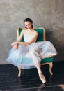 Ballet dancer ballerina in beautiful light blue dress tutu skirt posing sitting on vinage chair in loft studio Royalty Free Stock Photo