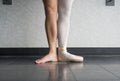 Ballet dancer in first position with one foot in a pointe shoe, and one bare leg