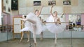 in ballet hall, girls in white ballet skirts are engaged at ballet, rehearse attitude, Young ballerinas standing on toes