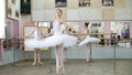 in ballet hall, girls in white ballet skirts are engaged at ballet, rehearse turning, Young ballerinas standing on toes