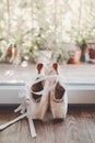 Ballet pointe shoes with pink silk ribbon near window. Old pointe shoes with satin ribbon