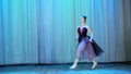 Ballet rehearsal, on the stage of the old theater hall. Young ballerina in lilac black dress and pointe shoes, dances