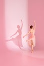 Balletic Beauty. Classic ballerina dances barefoot in pink dress against pastel pink background with her shadow.