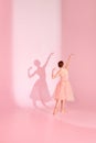 Balletic Grace. Classic ballerina dances barefoot in pink swimsuit and long skirt against pastel pink background with