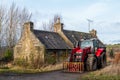 This is a modern Massey Ferguson Tractor parked beside a disused Farmhouse